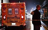 An FBI agent stands behind a police cordon and an ambulance outside the Tree of Life Synagogue (L) after a shooting there left 11 people dead in the Squirrel Hill neighborhood of Pittsburgh on October 27, 2018. (Brendan Smialowski / AFP)