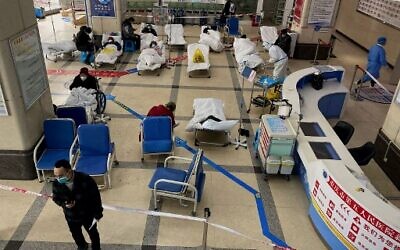 A man stands in front of a cordoned-off area, where COVID-19 patients lie on hospital beds, in the lobby of the Chongqing No. 5 People's Hospital in China's southwestern city of Chongqing on December 23, 2022. (Noel Celis/AFP)