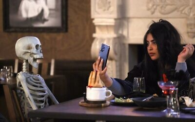 A woman takes pictures of a skeleton model seated at her table at the horror-themed 'Shadows' restaurant in the Saudi capital Riyadh's Boulevard entertainment city, January 19, 2022. (Fayez Nureldine / AFP)