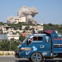 A truck drives as a plume of smoke rises from a building during a reported Russian airstrike on Syria's northwestern rebel-held Idlib province, on June 25, 2023. (Abdulaziz KETAZ / AFP)