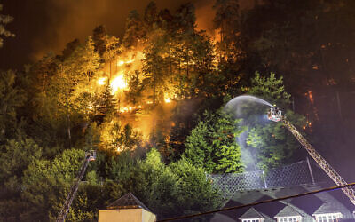 Firefighters throw water on fire in the Ceske Svycarsko (Czech Switzerland) National Park, above the village Hrensko, Czech Republic, Monday July 25, 2022. The fire broke out on Sunday and started spreading on Monday as the wind rose. (Hajek Vojtech/CTK via AP)