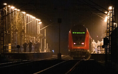 Forensics staff on duty at a platform by a regional train, with police officers standing opposite, following a deadly stabbing, at Brokstedt station in Brockstedt, Germany, January 25, 2023. (Jonas Walzberg/dpa via AP)