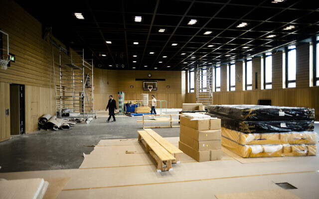 Rabbi Yehuda Teichtal, left, walks through the construction site of a huge indoor basketball court and gym that can be turned into a lecture hall for up to 600 people or a reception hall for weddings and bar mitzvahs, inside the new Jewish educational and cultural complex in Berlin, Germany, Monday, June 12, 2023. (AP Photo/Markus Schreiber)