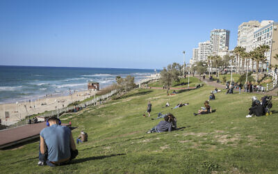 People sit alongside the Bat Yam promenade on March 4, 2017. (Issac Harari/Flash90)