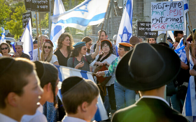 Israelis attend a protest against military service exemptions for ultra-Orthodox yeshiva students and the government's planned judicial overhaul, outside the Kol Torah yeshiva in Jerusalem, May 4, 2023. (Noam Revkin Fenton/Flash90)